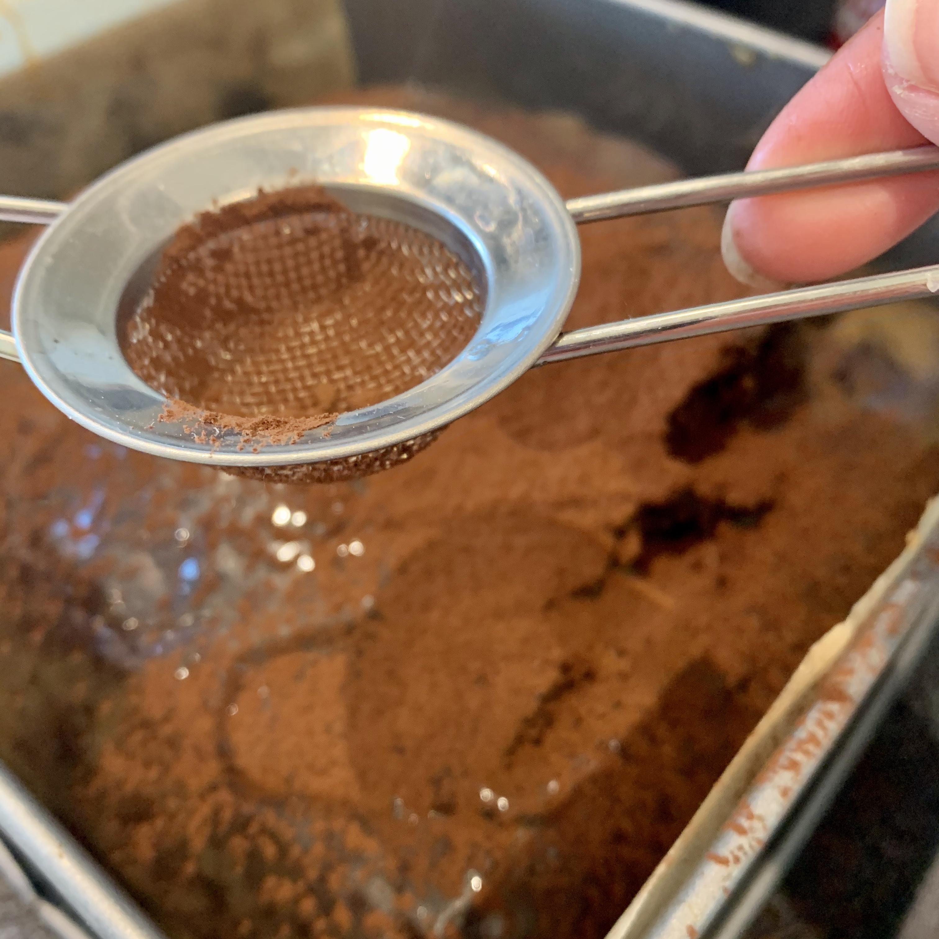 sieving cocoa powder over the cake